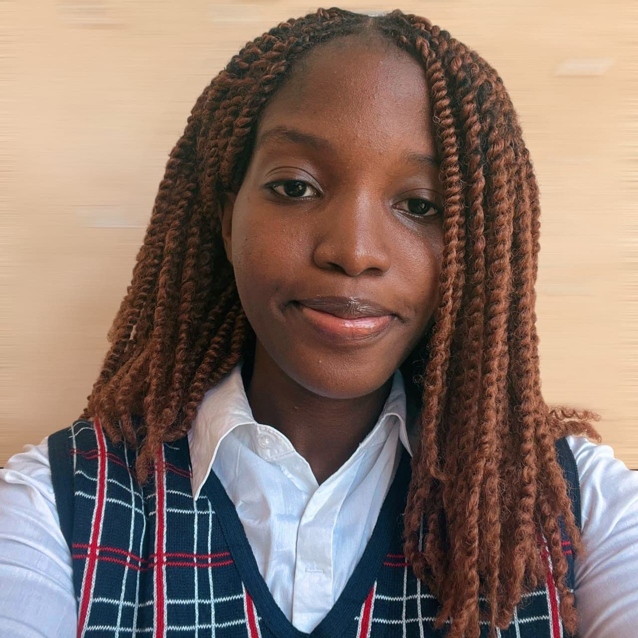 Omotola en uniforme scolaire, longues tresses, regard caméra.