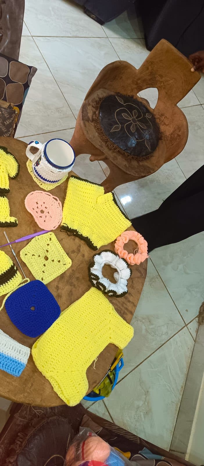 Un ouvrage de crochet jaune en cours, posé au sol à côté d’une tasse.
