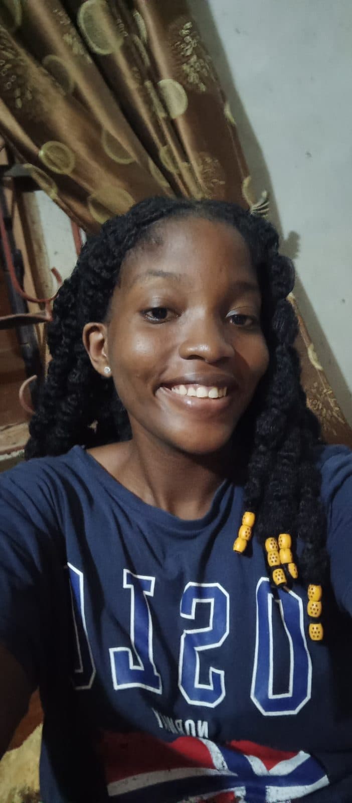 Omotola en grand sourire, sweat bleu marine.