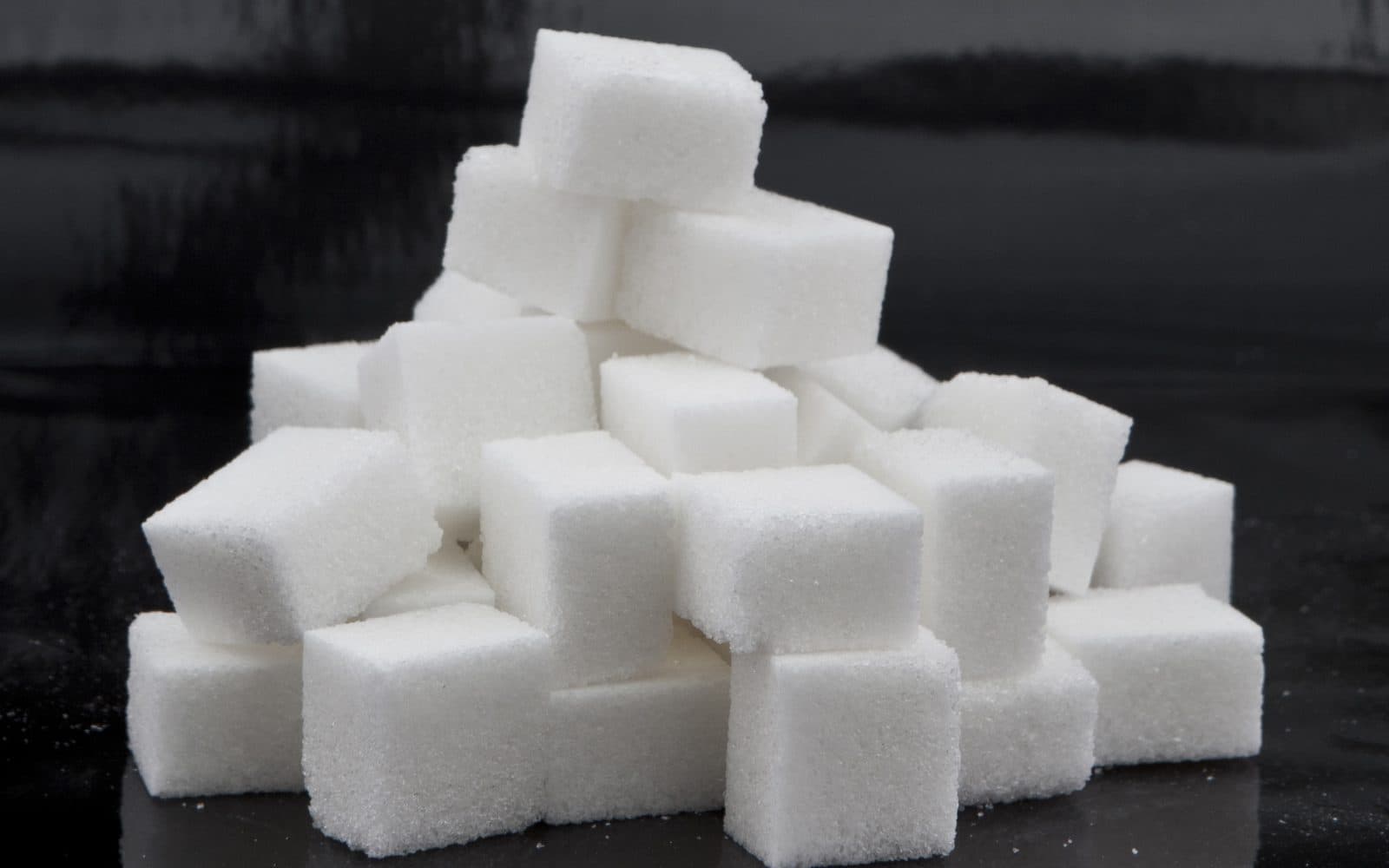 Une pyramide de morceaux de sucre sur un fond sombre.