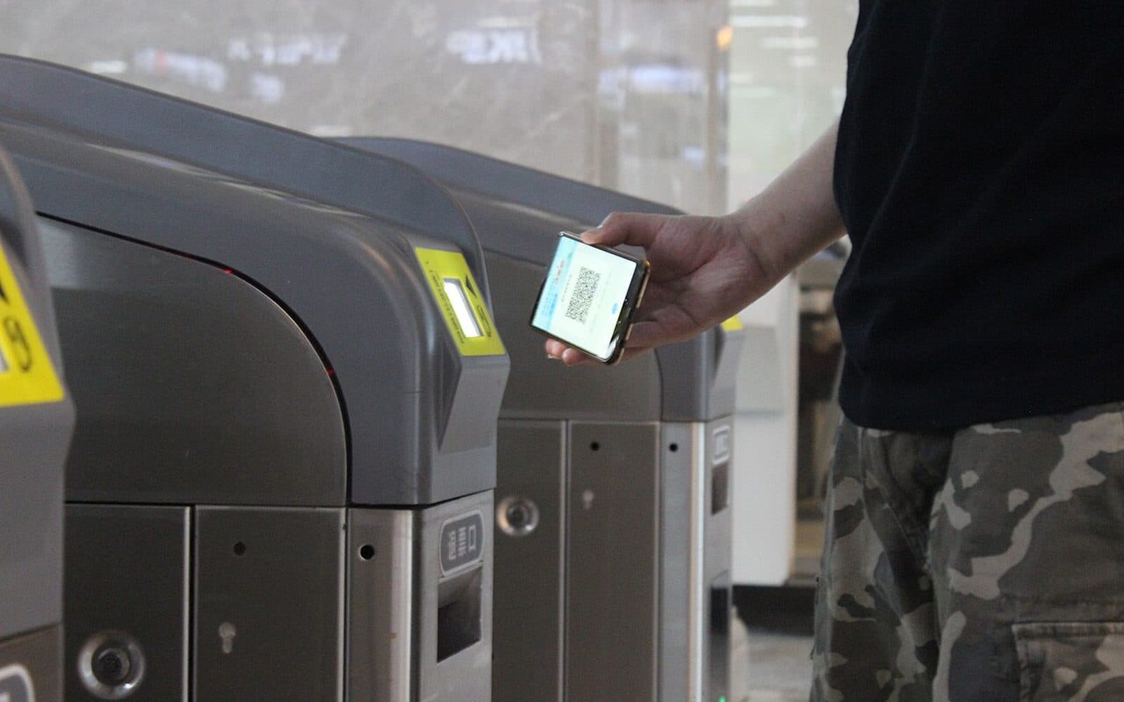 Un voyageur présente le code QR de son téléphone au portique du métro.