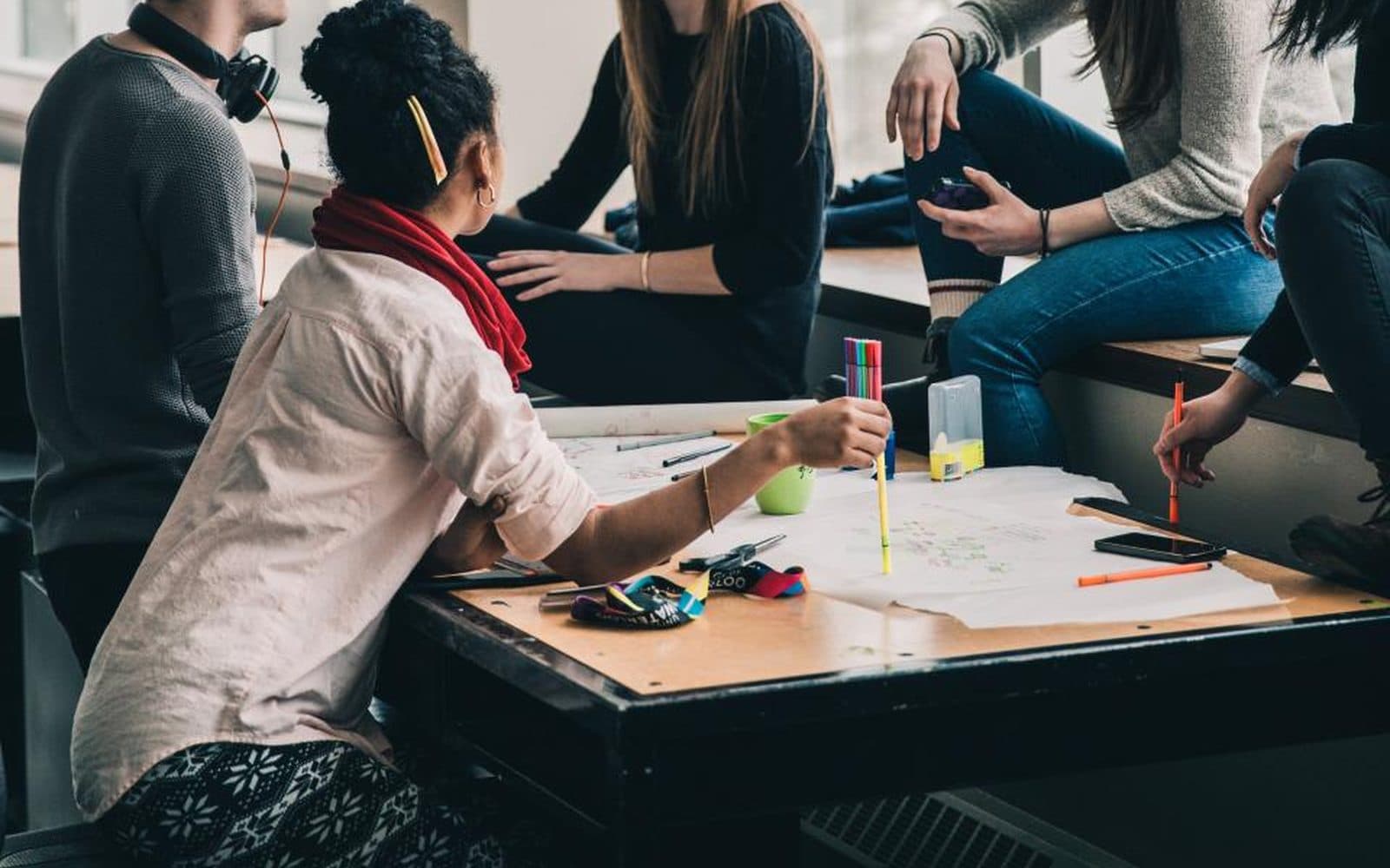 Des étudiants travaillent ensemble autour d’une table couverte de papiers.