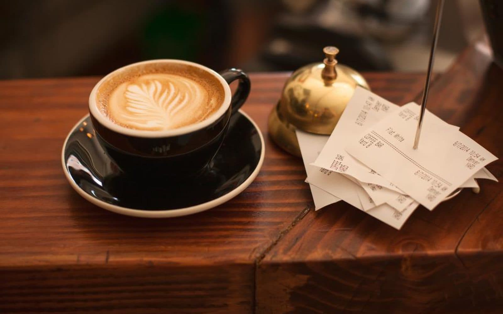 Une tasse de café, une clochette de comptoir et une pique de tickets de caisse.