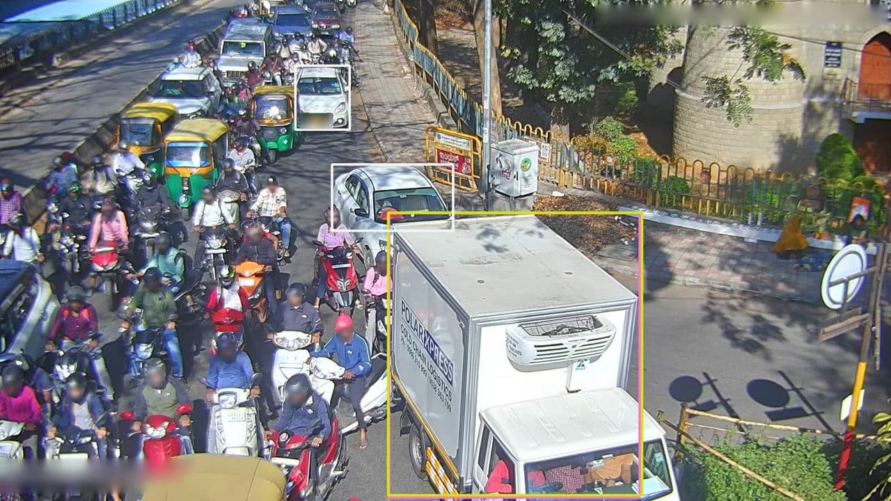 Une rue de Bengaluru saturée de motos et de voitures, filmée d’une caméra de vidéoprotection. Le modèle générique n’entoure que quatre véhicules, tous au premier plan.